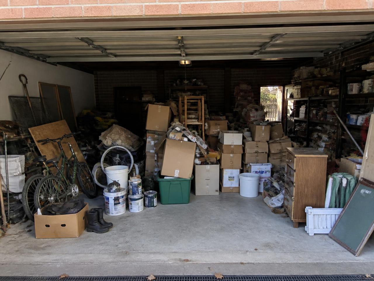 Suburban double garage packed with boxes, bikes, paint tins and old furniture